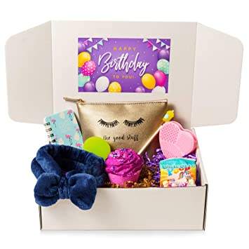 A Glamping-themed birthday gift box containing various items including a makeup pouch, a notebook, a hair scrunchie, a bath bomb, and candy, all arranged neatly in an open white box.