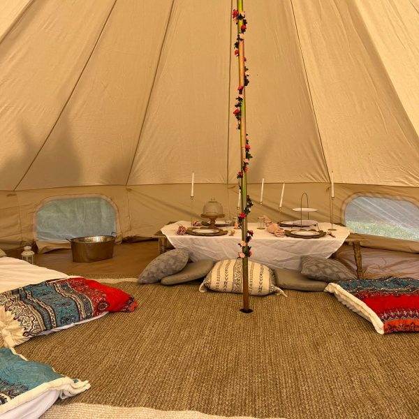 Interior of a Teepee with pillows and blankets on the floor.