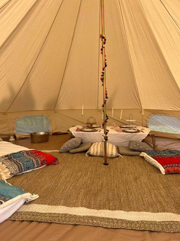 Interior of a Teepee with pillows and blankets on the floor.