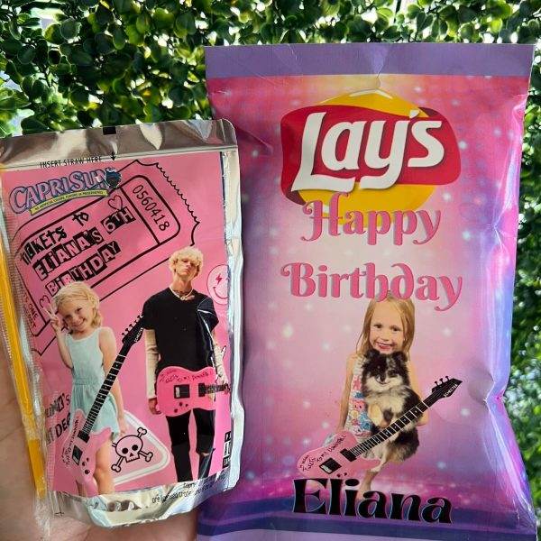 A hand holds two custom birthday snack packages: a Capri Sun juice pouch featuring nostalgic images labeled "mixtape", and a pink "292188731_1435129270244593_7973682324553567415_n" potato chip bag with a girl posing.