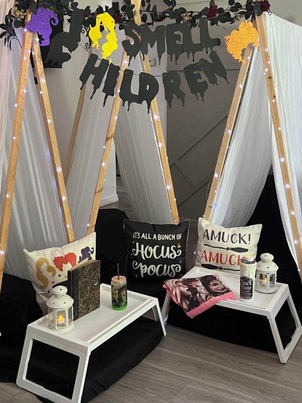 Halloween-themed indoor decor with sleepover tent rentals surrounded by themed pillows and signs, including "it's all a bunch of hocus pocus" and "amuck! amuck!" A Lakeland-inspired glamping room with a teepee tent.