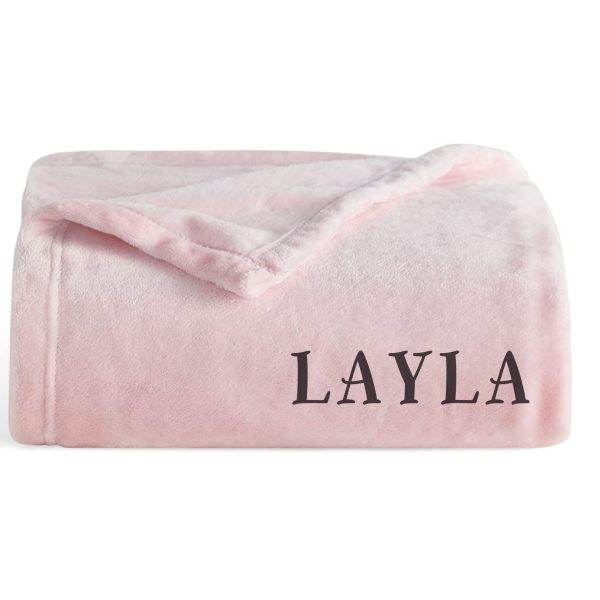 A Layla pink blanket, perfect for glamping, neatly folded with the name "layla" embossed in dark letters near the bottom edge.
