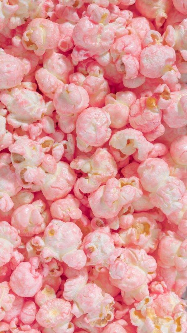 Close-up image of Perfect Pop Pink and White Popcorn, with a mixture of fully popped kernels and some partial pieces, showing a vibrant and colorful texture.