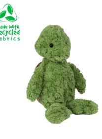 A green stuffed turtle with a logo on it, featuring the Build A Bestie Packages Add-on with a tag stating "made with recycled fabrics" on the top left corner. The toy, ideal for a "build a stuffed animal" party, is textured and appears soft.