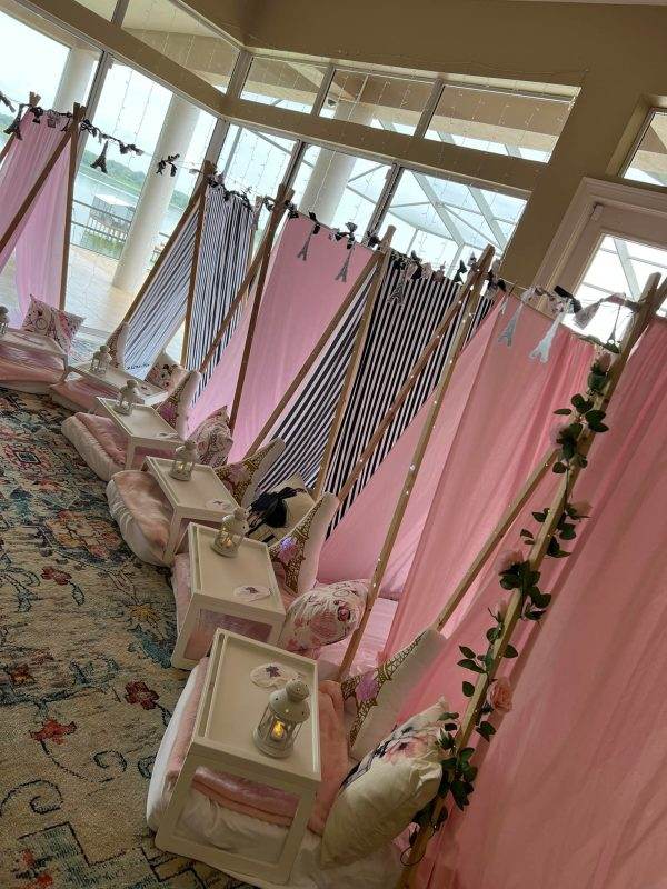 Elegant indoor wedding venue setup with rows of draped pink and white fabrics, adorned with floral decorations and soft lighting, different from typical offerings by other companies.