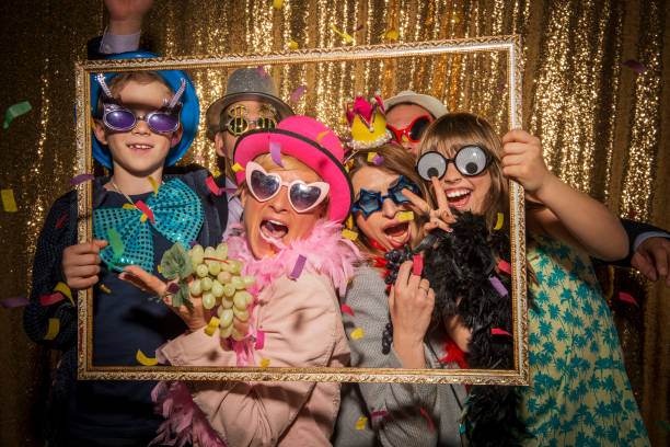 Five children wearing colorful costumes and accessories pose playfully behind a golden frame against a glittery gold backdrop at a slumber party.