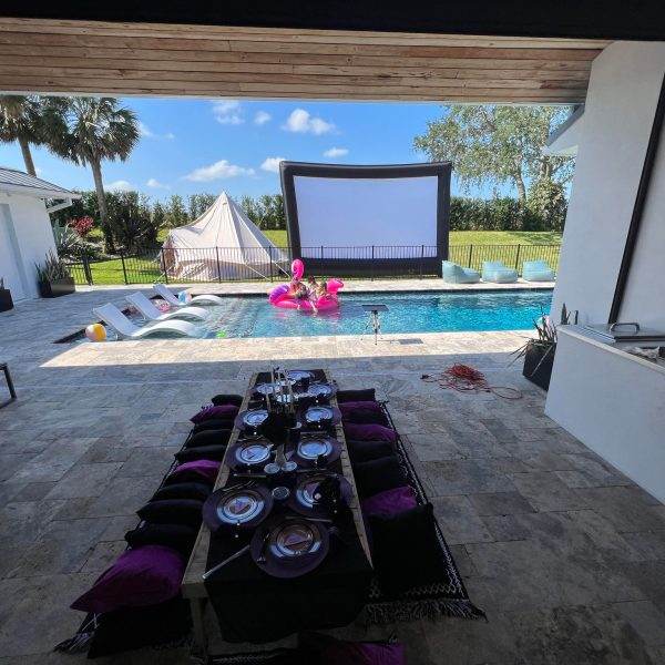 A backyard with a pool and a movie screen, perfect for glamping.