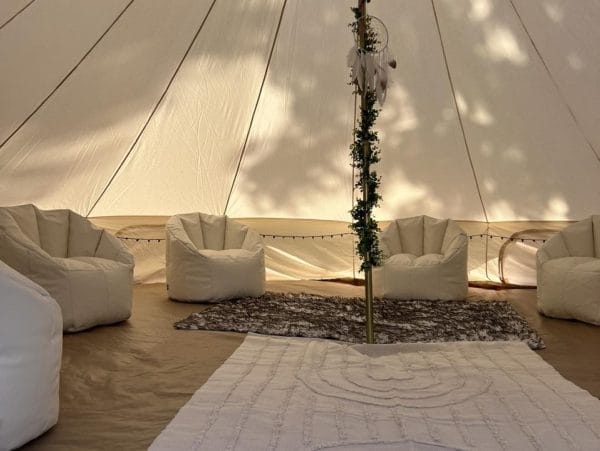A white Bell Tent with white chairs and a white rug.