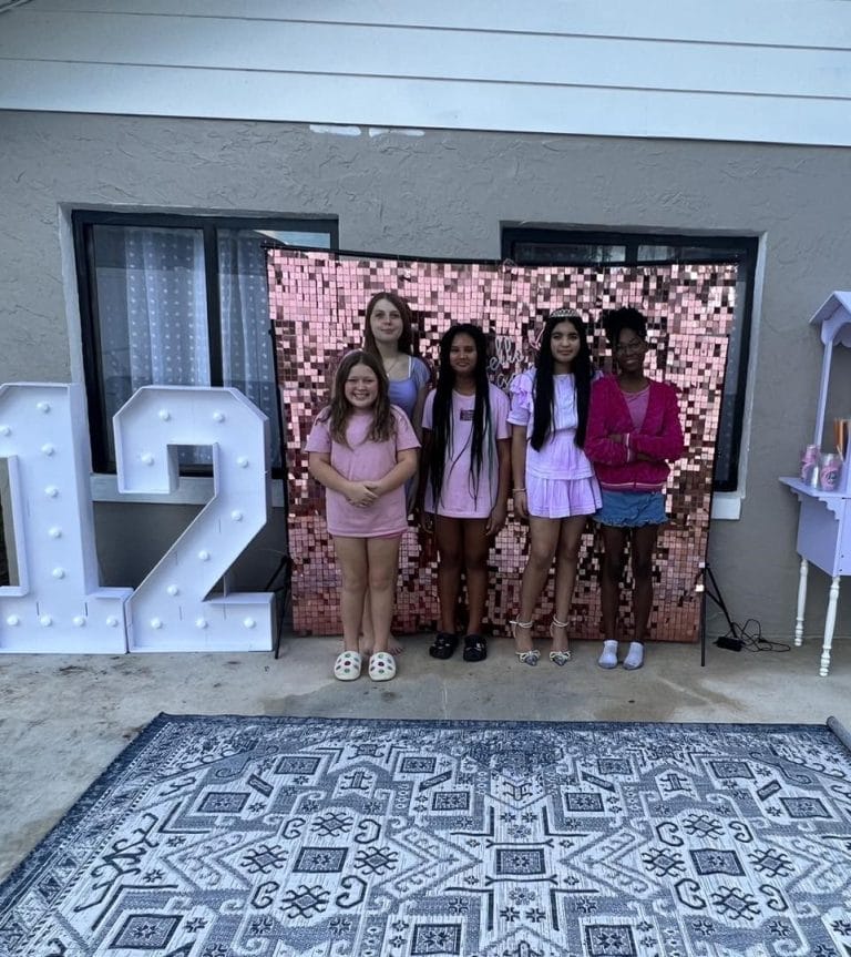 A group of girls standing in front of a large number 12 while having a party.