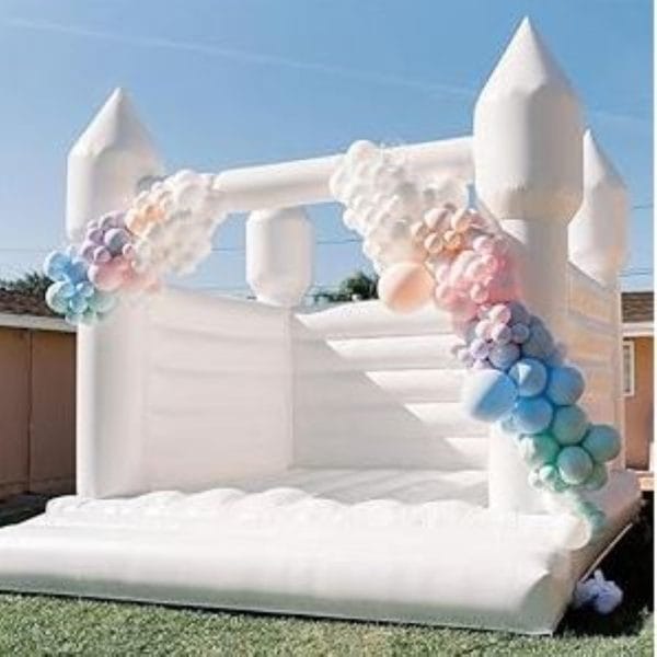 Majestic White Bounce House Castle with colorful balloon arches at the entrance, set up in a backyard.