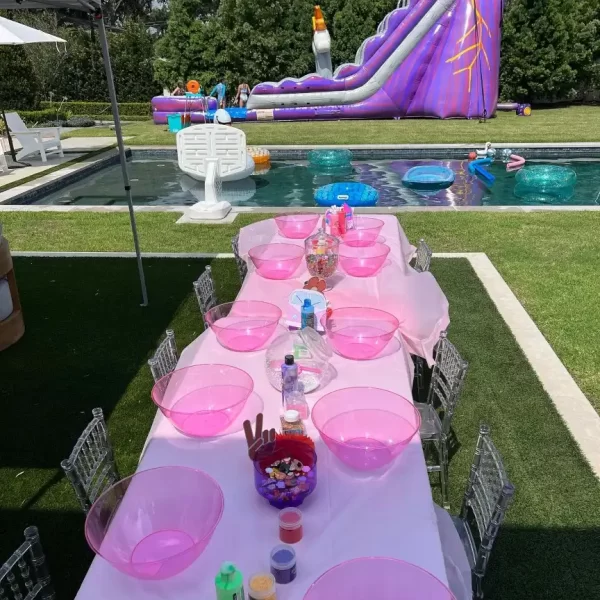 A table set up for a party with a water slide, perfect for pink-themed celebrations in Lakeland.