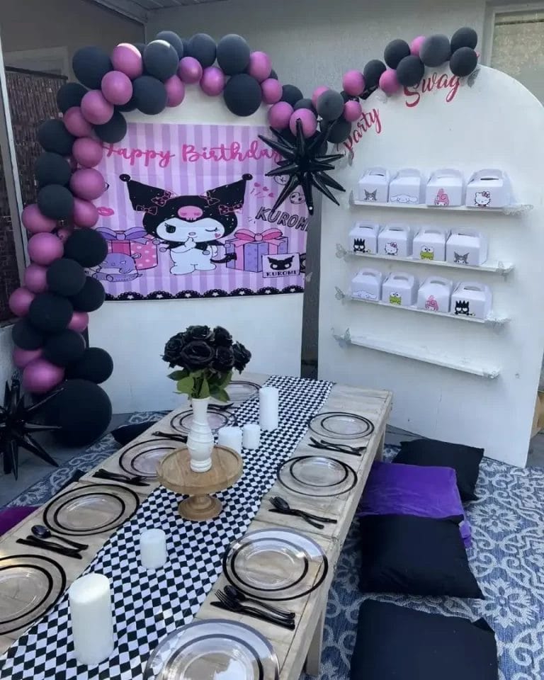 Outdoor birthday setup featuring a "happy birthday Aurora" banner with a cat motif, a balloon arch, and a dining table with black and white decor, perfect for kids parties in Central Florida.