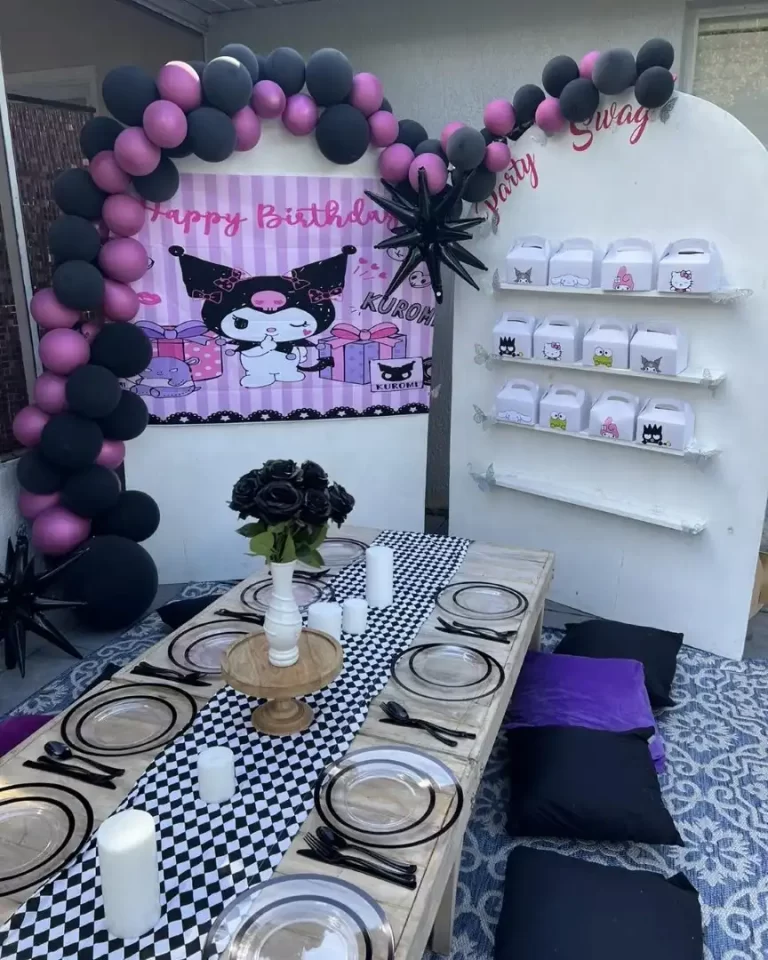 A table with black and purple balloons in a glamping setting.