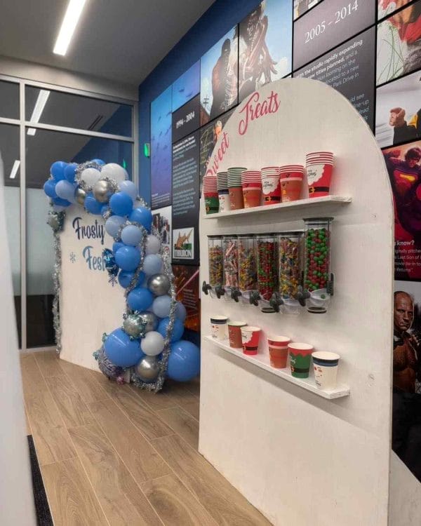 A colorful display of balloons and candies creates a festive atmosphere in an office.
