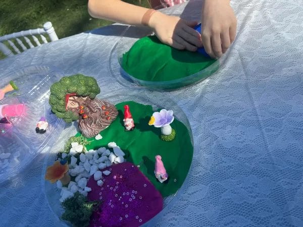 A little girl is making a Teepee fairy garden out of clay.