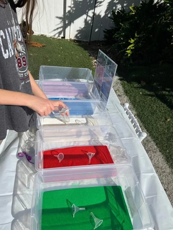 A girl is organizing plastic containers on a table at a glamping party.