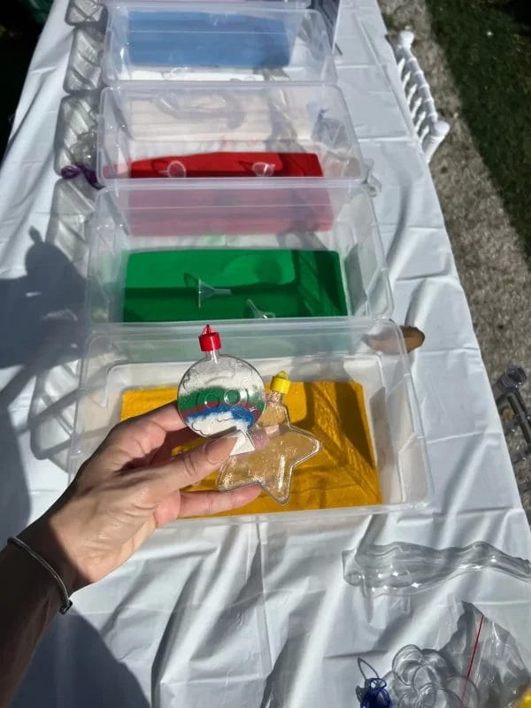 A person holding a tray of colored liquids while glamping in a bell tent.