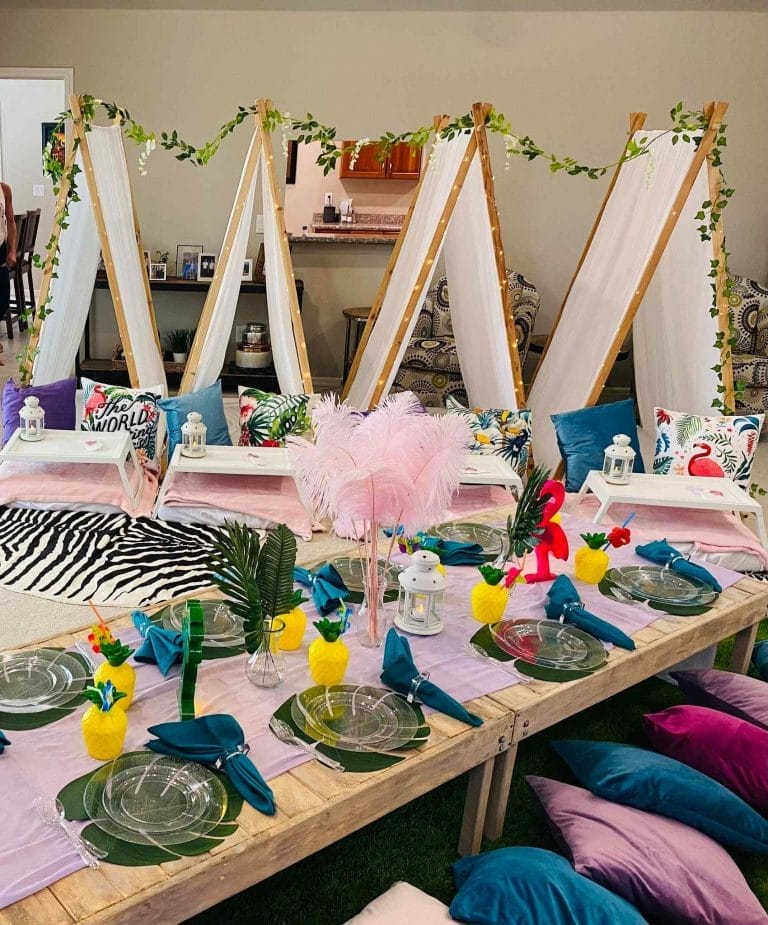 A vibrant and colorful Florida's Sleepover Party table setting with a tropical theme, featuring easels, decorative elements, and lush foliage.