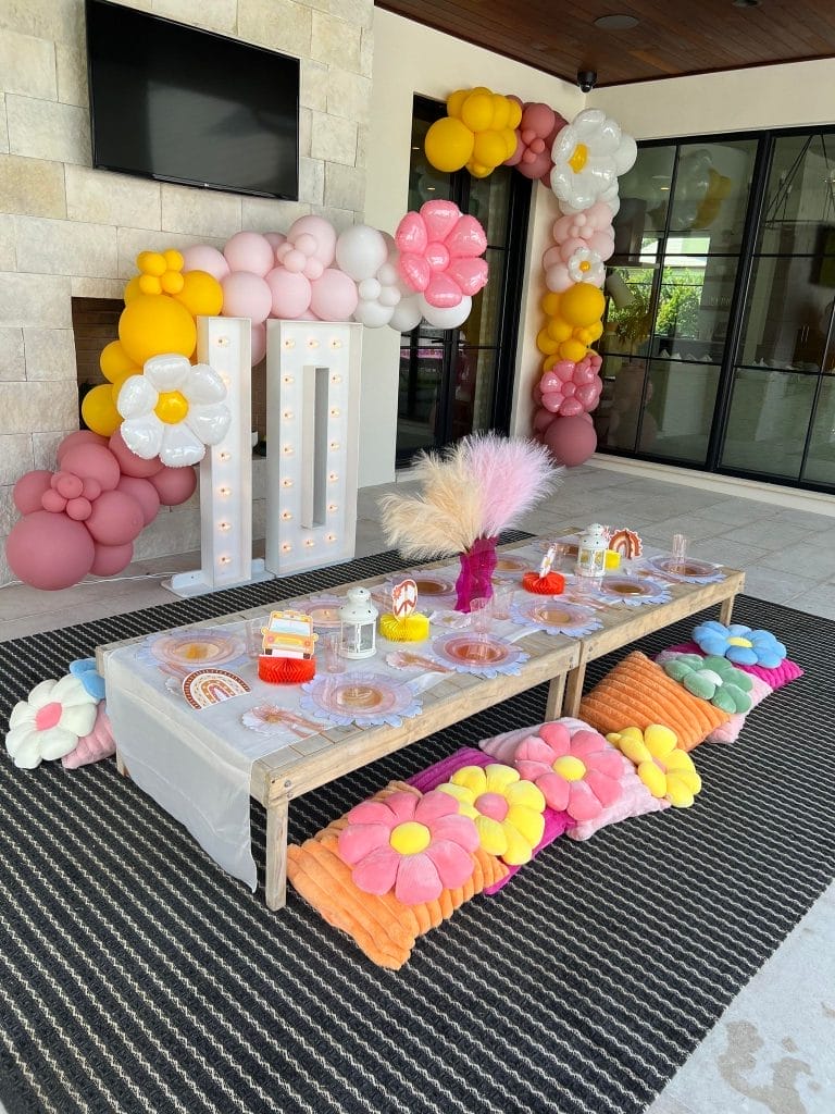 An Ultimate Sleepover-themed birthday party setup with a floral theme, featuring a decorated table with snacks and surrounded by balloon arrangements.