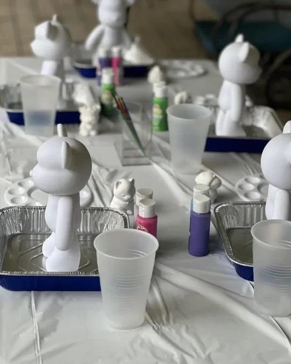 Barbie Themed Party vinyl figurines arranged on a table with paint supplies, ready for decoration in a crafting workshop.
