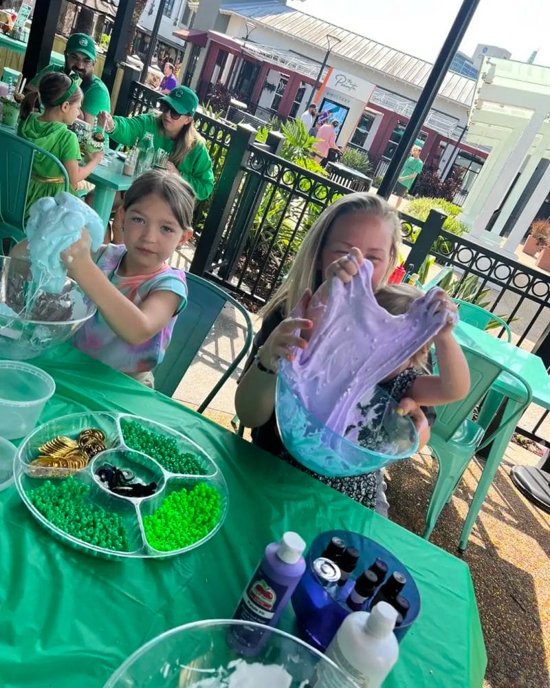 Children engaging in a slime-making activity at an outdoor event.