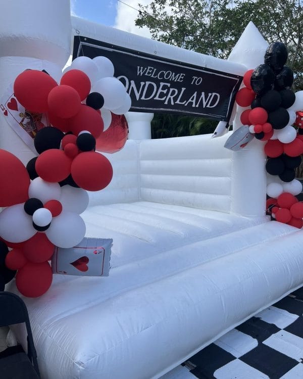 Inflatable entrance with "welcome to Wonderland Wonders" banner, adorned with black, white, and red balloons and playing card decorations.