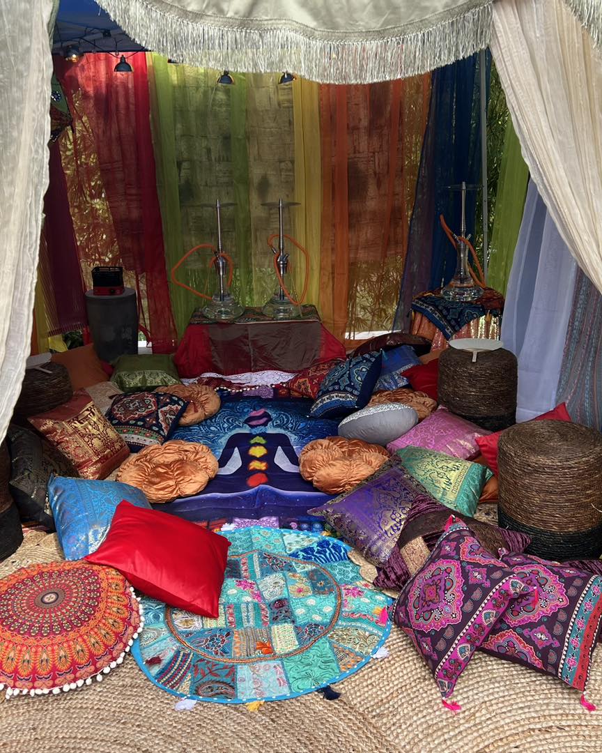 Colorful bohemian-style tent interior with assorted cushions, hanging drapes, and decorative rugs, creating a cozy, vibrant seating area for an ultimate night.