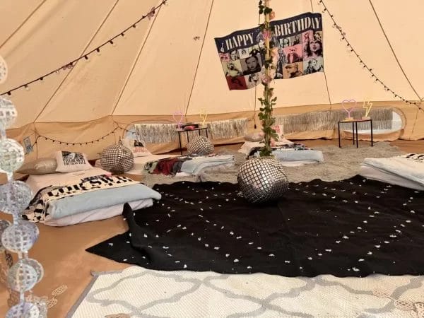 A cozy tent interior decorated for a **Dream Catcher Themed Party** with mattresses, cushions, disco balls, dream catchers, and a "happy birthday" banner.