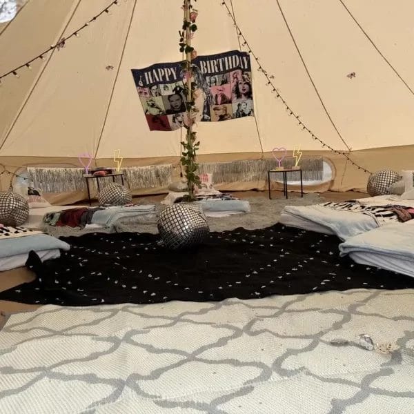 Interior of a tent decorated for a Dream Catcher Themed Party with multiple beds, a "happy birthday" banner, and Moroccan-style cushions.