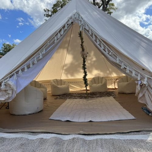 A white Bell Tent with a rug on the floor for a party.